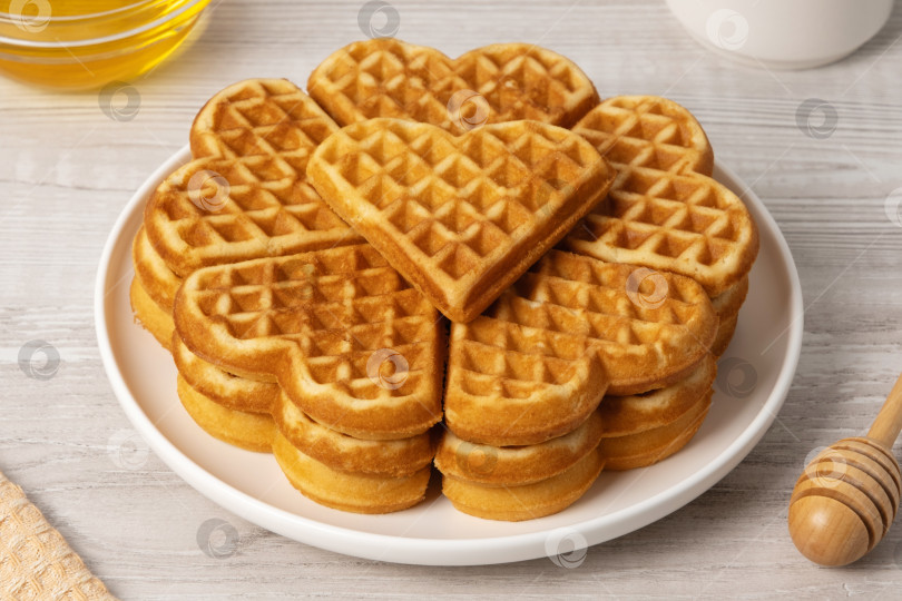 Скачать Вафли в форме сердечка подаются на тарелке с медом и сиропом рядом фотосток Ozero