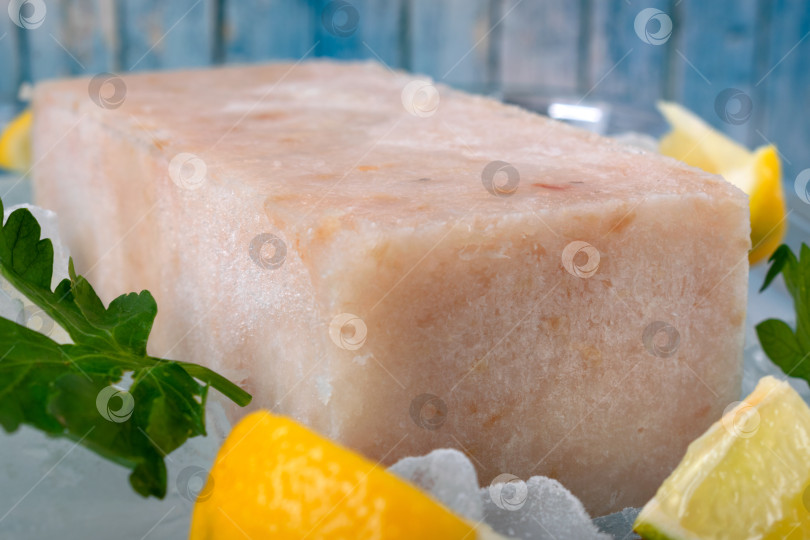 Скачать Замороженный рыбный фарш, нарезанный кубиками, с дольками лимона и петрушкой на льду фотосток Ozero