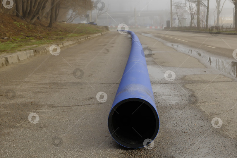 Скачать Пластиковая водопроводная труба перед уклакой в траншею. Ремононые работы в городе. фотосток Ozero
