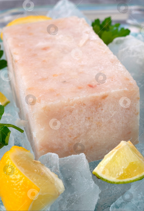 Скачать Замороженный рыбный фарш, нарезанный кубиками, с дольками лимона и петрушкой на льду фотосток Ozero
