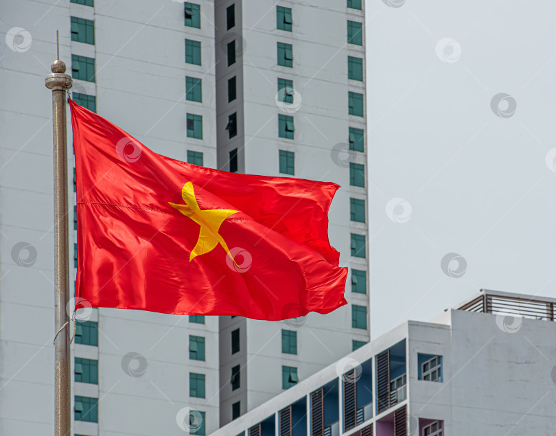 Скачать Вьетнамский флаг с красным фоном и жёлтой звездой. Видны здания отелей в Нячанге фотосток Ozero