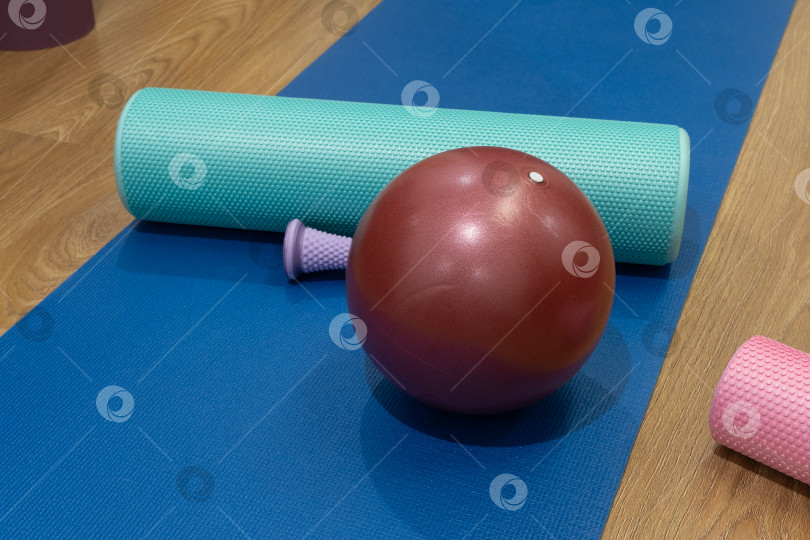 Скачать По утрам в тренажерном зале на синем коврике расставлены тренажеры с роликами и мячом. фотосток Ozero