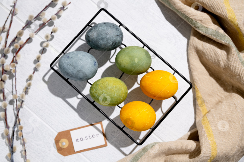 Скачать Пасхальные яйца, окрашенные естественным образом гибискусом и куркумой, сохнут на решетке для охлаждения, создавая красивую палитру желтых и зеленых оттенков, готовые к празднованию Пасхи фотосток Ozero