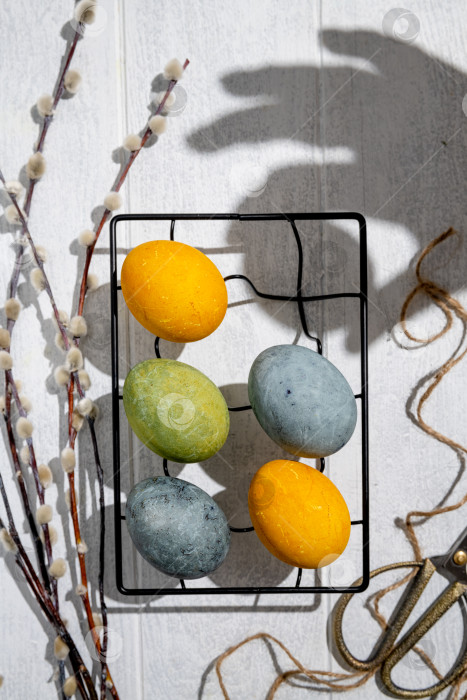 Скачать Пасхальные яйца, окрашенные естественным образом гибискусом и куркумой, сохнут на решетке для охлаждения, создавая красивую палитру желтых и зеленых оттенков, готовые к празднованию Пасхи фотосток Ozero