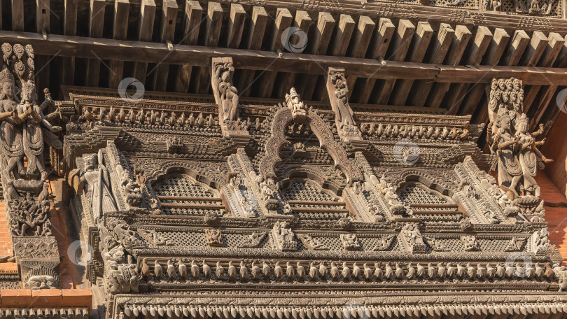 Скачать Уникальная резьба по дереву. Зарешеченные окна, красивые фигуры богов, птиц на фасаде здания. фотосток Ozero