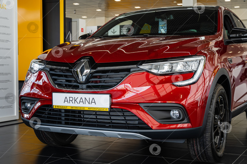 Скачать Салон красного внедорожника Renault Arkana. Крупный план передней части автомобиля с капотом, фарами и блестящей решеткой радиатора с логотипом Renault. Автосалон Renault в Мега Адыгея. фотосток Ozero