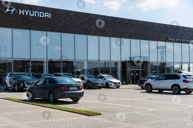 Скачать Подержанные автомобили Hyundai припаркованы возле автосалона Hyundai в Мега Адыгея. На фасаде здания автосалона надпись и логотип автопроизводителя Hyundai. фотосток Ozero