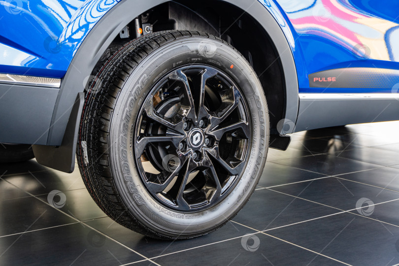 Скачать Синий внедорожник Renault Arkana в автосалоне. Шина Bridgestone установлена на литой алюминиевый обод. Крупный план заднего правого колеса. Автосалон Renault в Мега Адыгея. фотосток Ozero