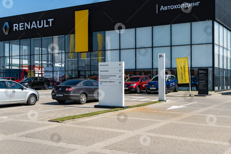 Скачать Новые автомобили Renault различных цветов припаркованы возле дилерского центра Renault. На фасаде здания есть надпись Renault с логотипом. Дилерский центр. Мега Адыгея. фотосток Ozero