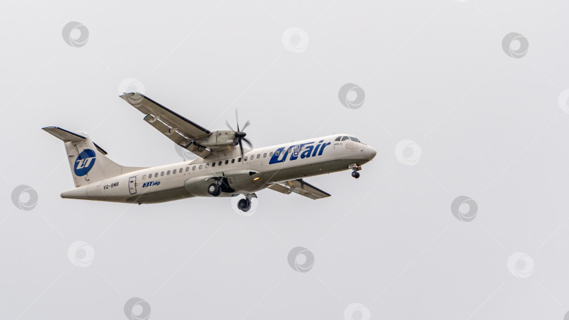 Скачать Самолет ATR-72 авиакомпании UTair в полете с выпущенными шасси. Самолет направляется к аэродрому Адлер для посадки. Крупный план шасси под фюзеляжем. Выборочный фокус, фотосток Ozero
