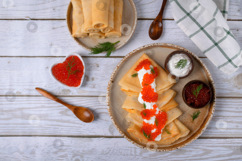 Скачать Традиционные русские тонкие блинчики (крепы) со сметаной и красной икрой на керамической тарелке фотосток Ozero