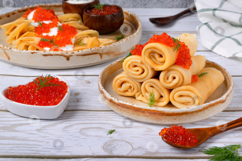 Скачать Традиционные русские тонкие блинчики с красной икрой на керамической тарелке фотосток Ozero