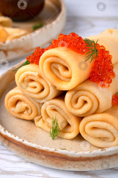 Скачать Традиционные русские тонкие блинчики с красной икрой на керамической тарелке на белом фоне фотосток Ozero