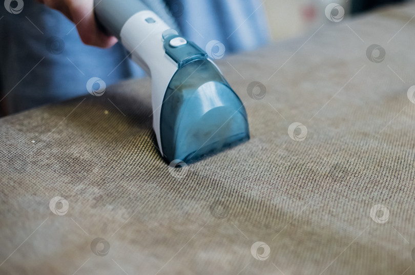 Скачать Крупный план влажной уборки грязным диваном с помощью сухого пылесоса. Домашняя уборка. фотосток Ozero