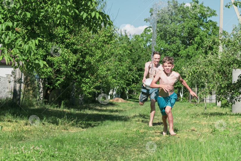 Скачать Два брата поливают водой участок за городом фотосток Ozero