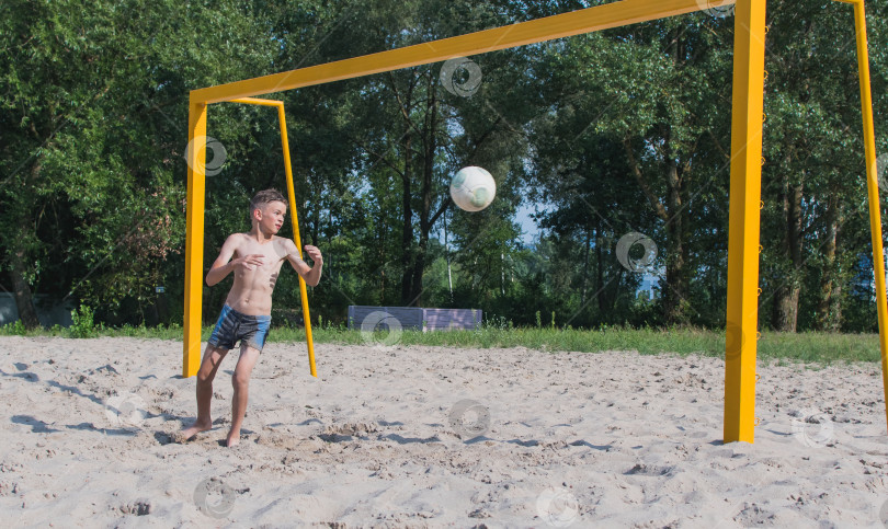 Скачать Маленький мальчик играет в футбол на песке фотосток Ozero