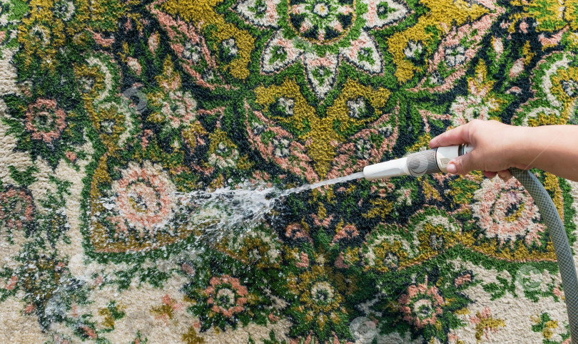 Скачать Женщина стирает ковер под проточной водой фотосток Ozero