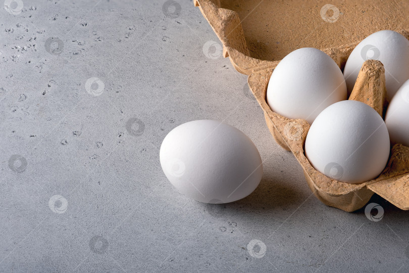 Скачать Одно яйцо в картонной упаковке на серой поверхности фотосток Ozero