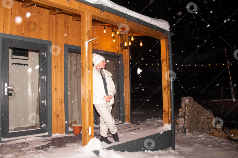 Скачать Снежной зимней ночью на террасе загородного дома стоит женщина фотосток Ozero