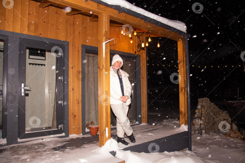 Скачать Снежной зимней ночью на террасе загородного дома стоит женщина фотосток Ozero