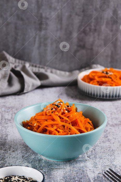 Скачать Корейская морковь с кунжутом в миске на столе в вертикальном положении фотосток Ozero