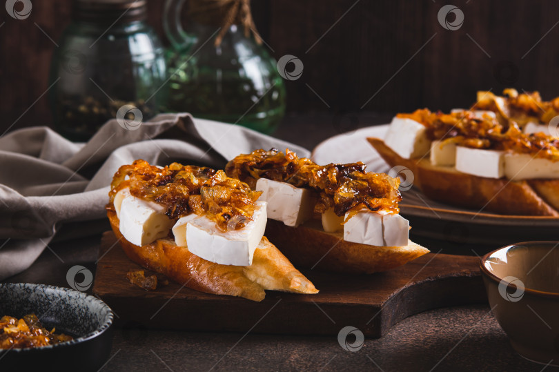 Скачать Бутерброды со сливочным сыром бри и карамелизированным луком на деревянной доске фотосток Ozero