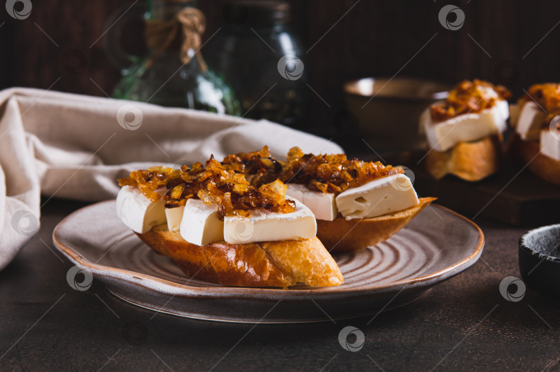 Скачать Закусочные бутерброды с сыром бри и карамелизированным луком на тарелке на столе фотосток Ozero