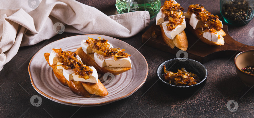 Скачать Закусочные сэндвичи с сыром бри и карамелизированным луком на тарелке на веб-баннере table фотосток Ozero
