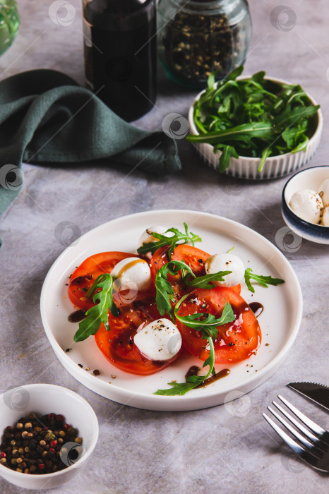 Скачать Салат капрезе с помидорами, моцареллой и рукколой на тарелке на столе, вид сверху фотосток Ozero