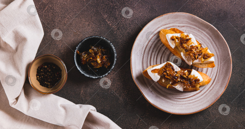 Скачать Тосты со сливочным сыром бри и карамелизированным луком на тарелке вид сверху веб-баннер фотосток Ozero