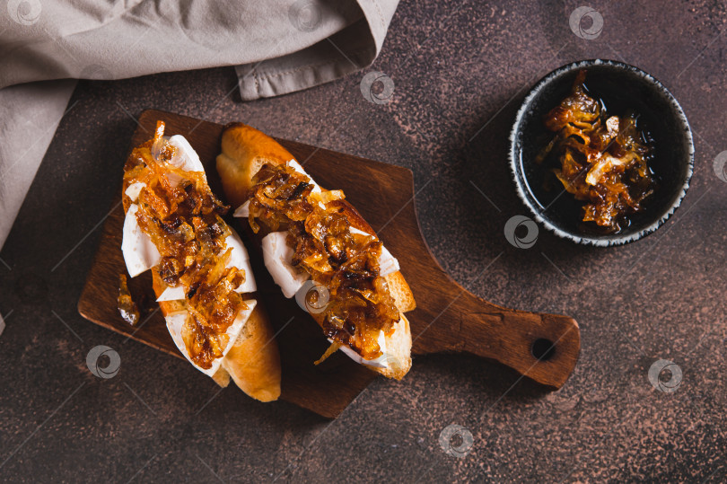 Скачать Бутерброды со сливочным сыром бри и карамелизированным луком на деревянной доске вид сверху фотосток Ozero