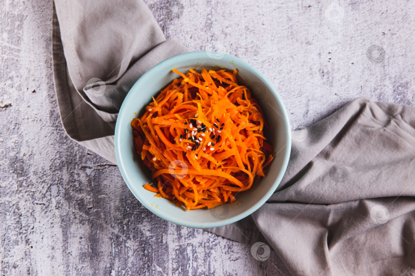 Скачать Крупный план корейской моркови с кунжутом в миске на столе вид сверху фотосток Ozero