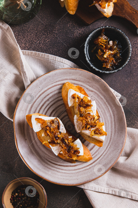 Скачать Тосты со сливочным сыром бри и карамелизированным луком на тарелке в вертикальном положении фотосток Ozero