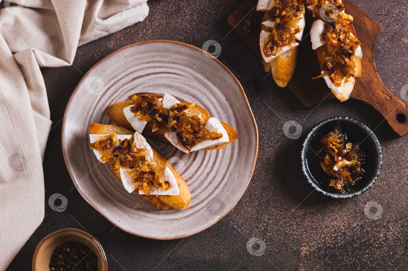 Скачать Закусочные сэндвичи с сыром бри и карамелизированным луком на тарелке на столе вид сверху фотосток Ozero