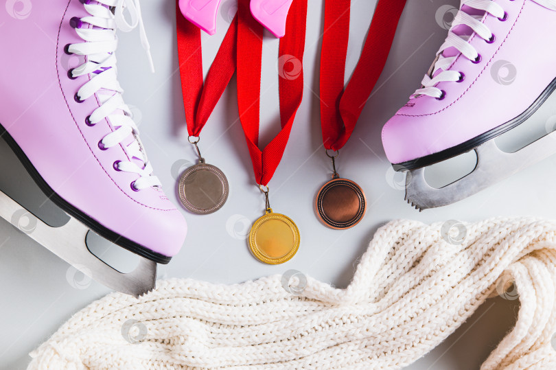 Скачать Крупный план фигуристых коньков, чехлов и трех медалей на светлом фоне, вид сверху фотосток Ozero