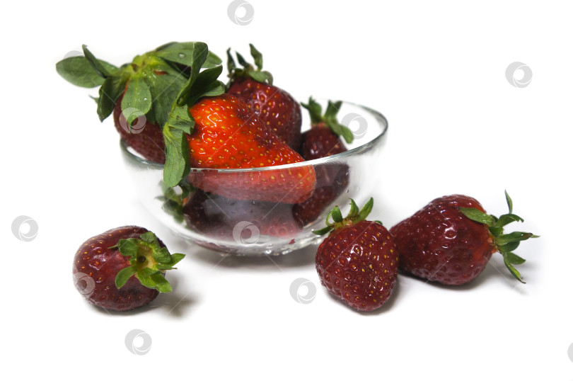 Скачать Свежая клубника в стеклянной вазе и рассыпанные ягоды на белом фоне фотосток Ozero