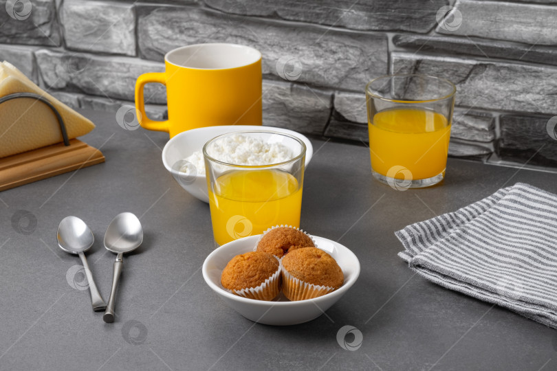 Скачать Апельсиновый сок, кофе, кексы и творог на сером столе фотосток Ozero