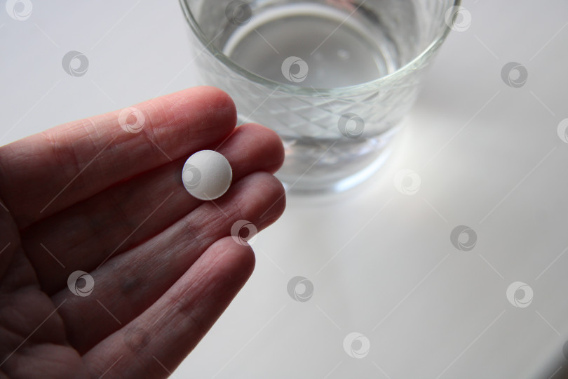 Скачать таблетка у меня в руке, стакан воды рядом., фотосток Ozero