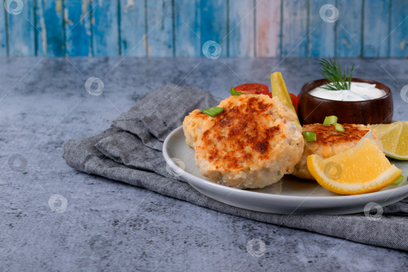 Скачать Обжаренные рыбные котлеты подаются со свежими овощами, дольками лимона и сметанным соусом фотосток Ozero