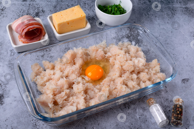 Скачать Фарш из белой рыбы, куриного яйца, бекона, сыра и зелени на сером столе. Пошаговое приготовление, шаг 1 фотосток Ozero