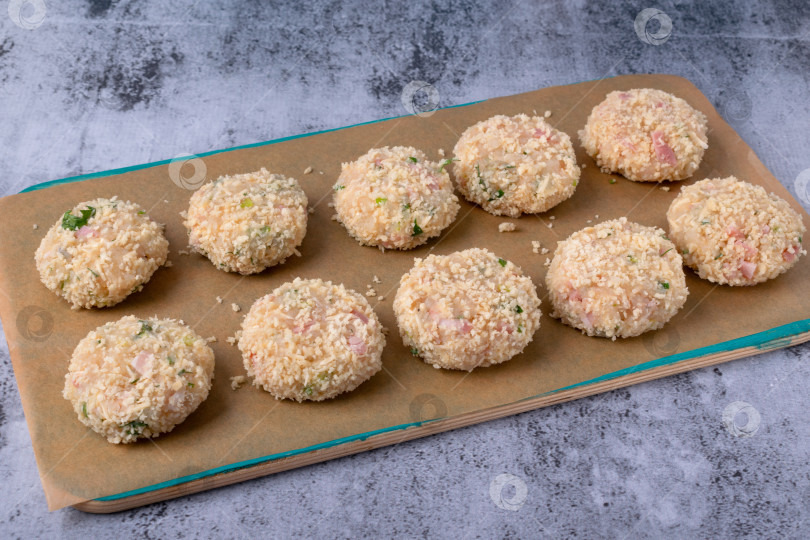 Скачать Выложите сырые котлеты на пергаментную бумагу на сером столе. Пошаговое приготовление, шаг 3 фотосток Ozero