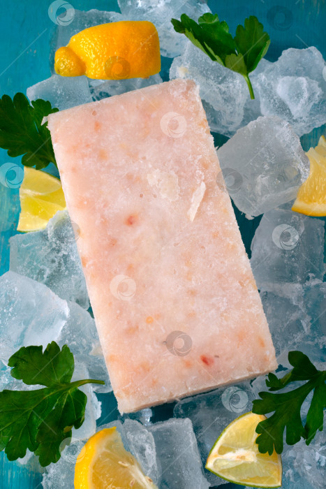 Скачать Замороженный рыбный фарш, нарезанный кубиками, с дольками лимона и петрушкой на льду фотосток Ozero