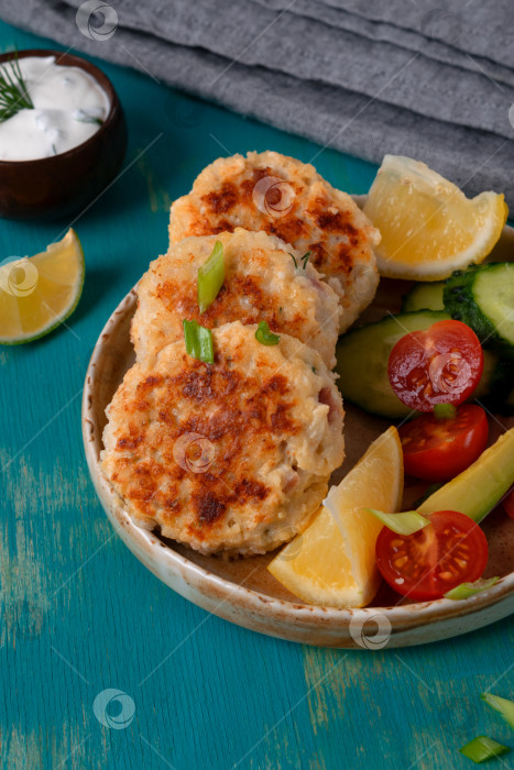 Скачать Жареные рыбные котлеты с беконом, сыром и зеленью на керамической тарелке фотосток Ozero