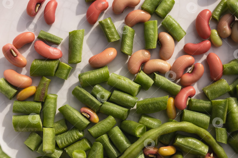 Скачать Измельченную зеленую стручковую фасоль и розовую фасоль выложить на белую керамическую поверхность фотосток Ozero