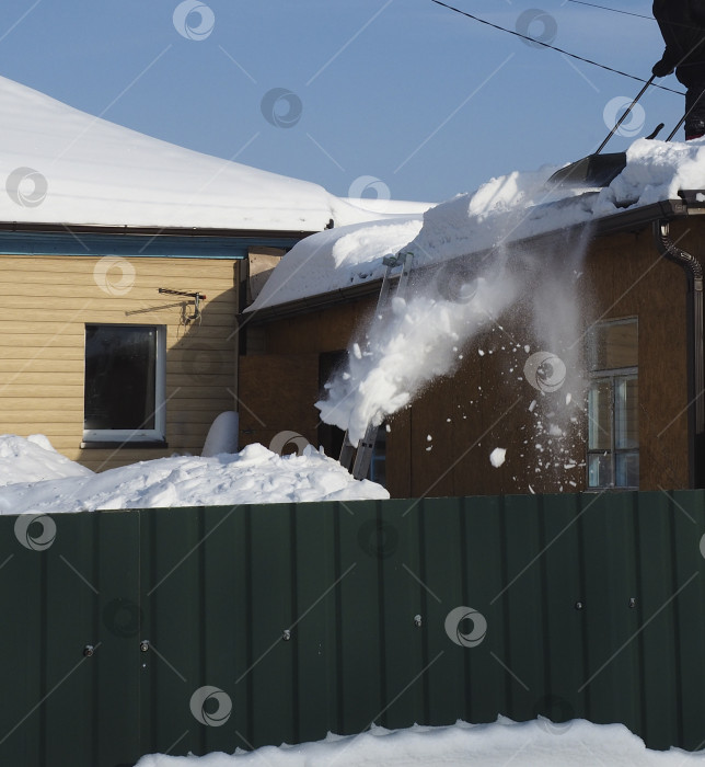 Скачать один мужчина убирает с крыши  частного дома снег фотосток Ozero