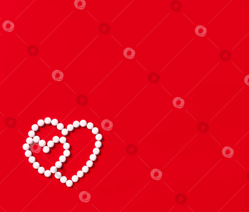 Скачать Два сердечка из круглых белых таблеток на красном фоне фотосток Ozero