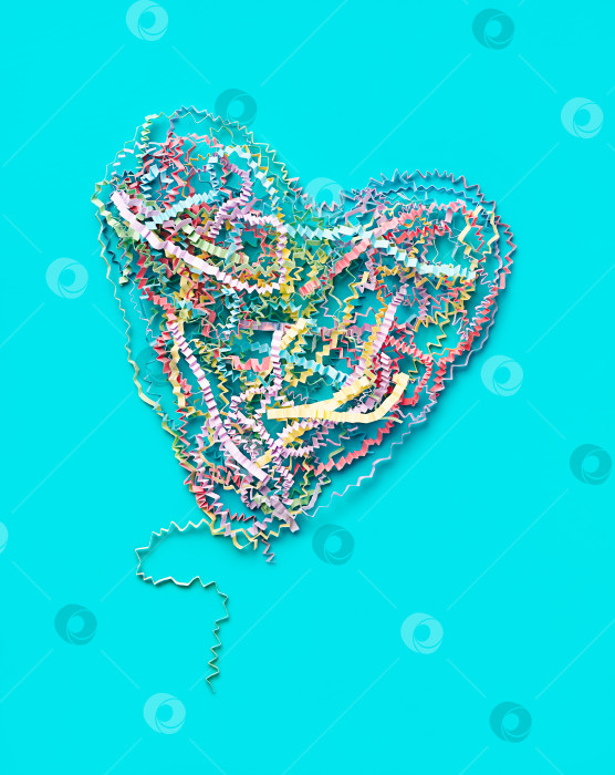 Скачать сердечко, сложенное из цветной гофрированной бумажной ленты, на синем бумажном фоне фотосток Ozero