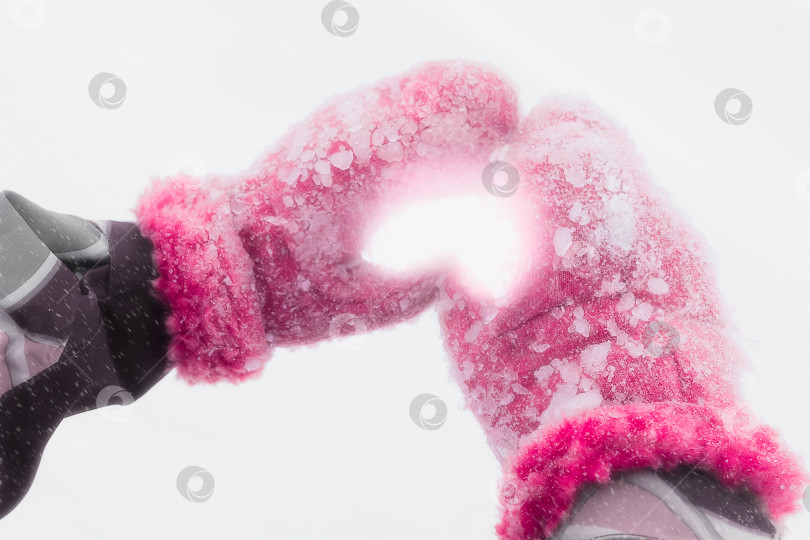 Скачать Детские ручки в заснеженных красных варежках сложены в форме сердца фотосток Ozero