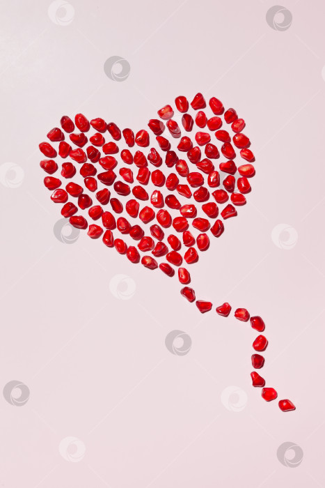 Скачать Сердце из зерен красного спелого граната на розовом фоне фотосток Ozero