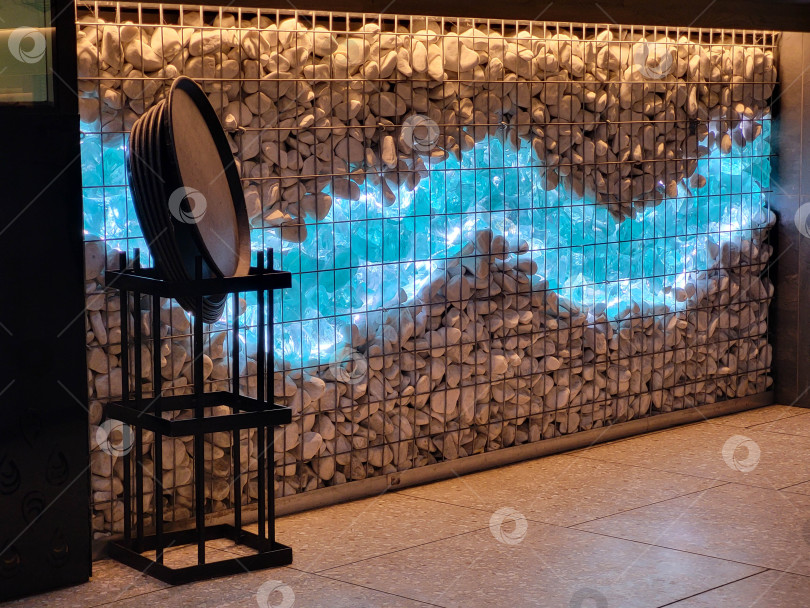 Скачать Россия, Ярославль, 10.01.2026 Декоративный габион в кафе с эрклезом и подсветкой. Штучное стекло эрклез блю и камни фотосток Ozero